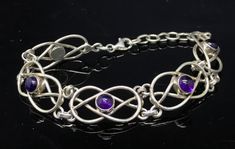 a silver bracelet with purple stones on it