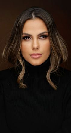 a woman with long hair wearing a black turtle neck sweater and posing for the camera