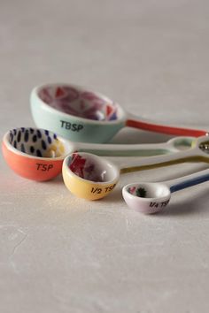 three bowls with spoons in them sitting on a counter top next to each other