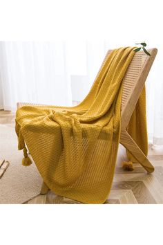 a yellow blanket sitting on top of a wooden chair