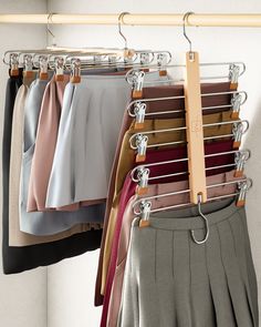 a rack full of different colored shirts and pants hanging on clothes racks with wooden hangers