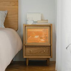 a nightstand with an orange heater on it next to a bed