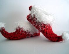 two crocheted red and white slippers sitting next to each other on a table