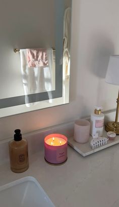 a bathroom counter with a candle, soap and other personal care items sitting on it