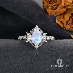 a ring with an opal stone surrounded by diamonds on top of a black cloth