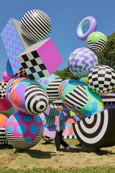 a man standing in front of an array of large, multicolored balloons on display