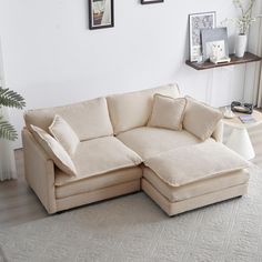 a living room with a sectional couch and coffee table in front of white walls, framed pictures on the wall