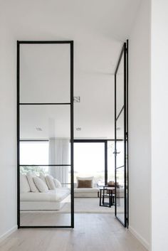 a white room with black framed glass doors and wood flooring is featured in the article, custom wooden doors