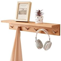 a pair of headphones hanging from a wooden shelf next to a potted plant