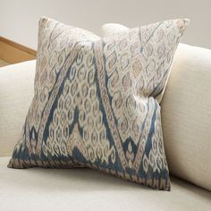 a blue and beige pillow sitting on top of a white couch