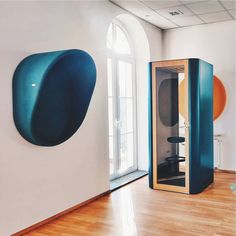 a room with a large blue object on the wall next to a window and wooden floor