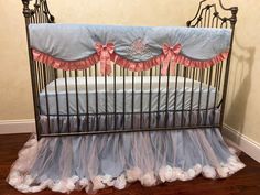 a baby crib with blue and pink ruffles on the bottom, along with white pillows