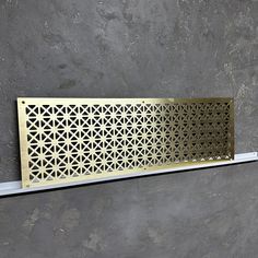 a decorative metal grille on the side of a wall in a room with concrete walls