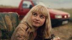 a woman sitting in front of a red truck