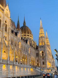 a large building with many spires lit up at night in front of a street