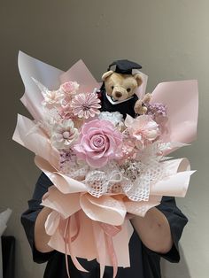 a teddy bear holding a bouquet of flowers in it's hands and wearing a black hat