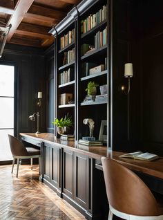 a home office with black walls and wooden flooring, built in bookshelves