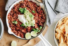 a skillet filled with chili and guacamole on top of a wooden table