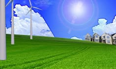 a green field with wind turbines and houses in the background under a blue cloudy sky