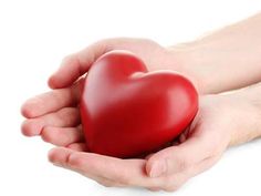 two hands holding a red heart in the palm of another person's hand on a white background