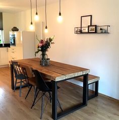 a kitchen table with chairs and a vase filled with flowers sitting on top of it