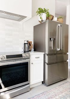 a silver refrigerator freezer sitting next to a stove top oven in a white kitchen