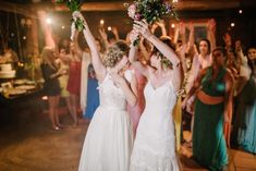 two bridesmaids holding bouquets in front of their faces as they walk down the dance floor