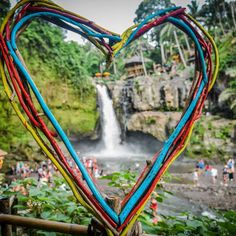 a heart - shaped frame made out of colored stream ribbons in front of a waterfall