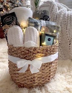 a wicker basket filled with white towels and other items on a fur rug next to a christmas tree