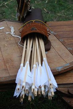 several arrows are laid out on top of a wooden table with an umbrella in the background