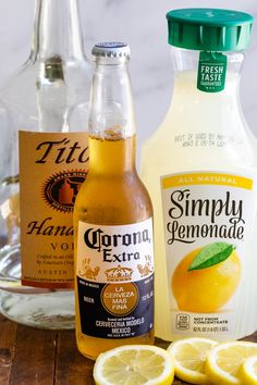 three bottles of lemonade sitting on top of a table next to sliced lemons