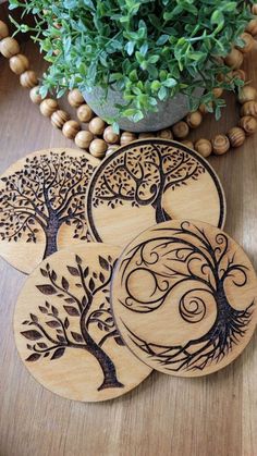 four wooden coasters with tree designs on them sitting next to a potted plant