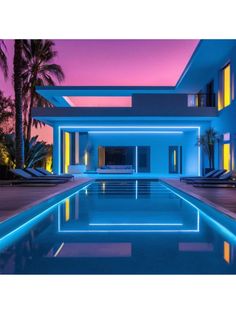 a large swimming pool in front of a modern house at night with lights on it