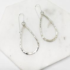 "These contemporary earrings consist of Sterling silver wire formed by hand into teardrops, and hammered to reflect the light beautifully. They are attached to a wire ear hook, which shows them off and ensures a lightweight dangle for every day wear.  - 50mm drop - quality ear-hook - hypoallergenic  - 925 Sterling Silver  - Hand Made Item The perfect pair to finish off your every day street style or minimalist wardrobe.  As you aware that each earring is forged by hand, therefore ever so slightly different from one another to give it an uniqueness about it.  Your earrings comes with a \".925\" sterling silver stamp as a symbol of guaranteed product quality as well as beautifully packaged in a branded box, ready for gifting, or spoiling yourself with a personalized piece. Free polishing clo Hand Forged Teardrop Earrings As Gift, Hand Forged Teardrop Earrings For Gift, Hammered Teardrop Earrings, Silver Hammered Teardrop Dangle Earrings, Hammered Teardrop Metal Earrings, Hand-forged Teardrop Hoop Earrings, Hammered Long Drop Teardrop Earrings As Gift, Hammered Metal Teardrop Earrings, Hammered Long Drop Teardrop Earrings For Gift