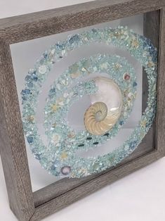 a wooden frame with sea glass and seashells in it