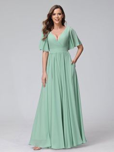 a woman wearing a long green dress with flutter sleeves and a v - neckline