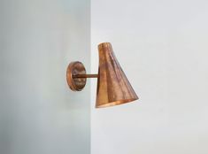 a wall mounted light with a wooden shade on it's side and a white wall in the background