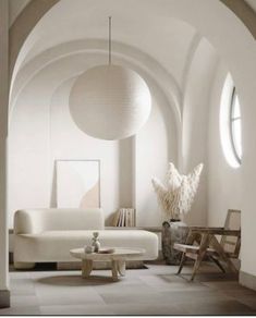 a living room filled with white furniture and large round lamps hanging from the ceiling above