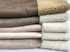 several blankets stacked on top of each other in different colors and sizes, all folded together