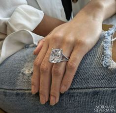 a close up of a person's hand with a diamond ring on their finger