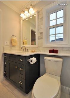 a white toilet sitting next to a bathroom sink under a mirror and a vanity with drawers