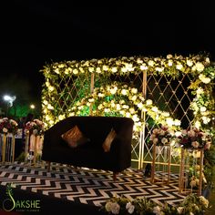 a black couch sitting in front of a white and gold flower covered wall at night