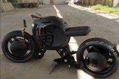 a black motorcycle is parked on the side of the road with wheels attached to it