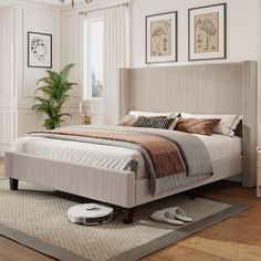 a bed sitting on top of a wooden floor next to a lamp and pictures above it