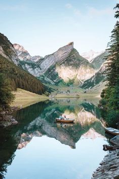 a boat floating on top of a lake surrounded by mountains