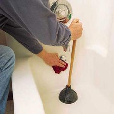 a man is using a plunger to clean a bathtub