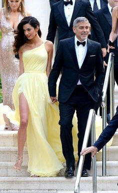 the couple are walking down the stairs together in formal wear and tuxedos,