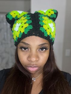 a woman wearing a green and yellow crocheted hat with ears on her head