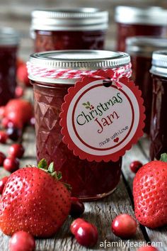 christmas jam with strawberries and cranberries around it on a wooden table surrounded by other jars