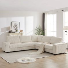 a living room with a white couch and rugs on the wooden floor next to windows